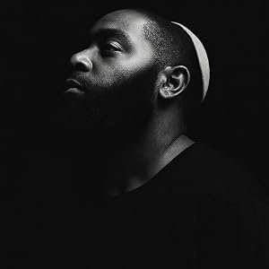public-relations-Algenaun-Benham-profile-Black and white profile portrait of a man with a beard, wearing a black shirt and a kippah, looking upwards and to the left against a dark background.